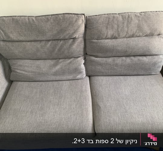 ספה אפורה נקייה על רקע קיר לבן